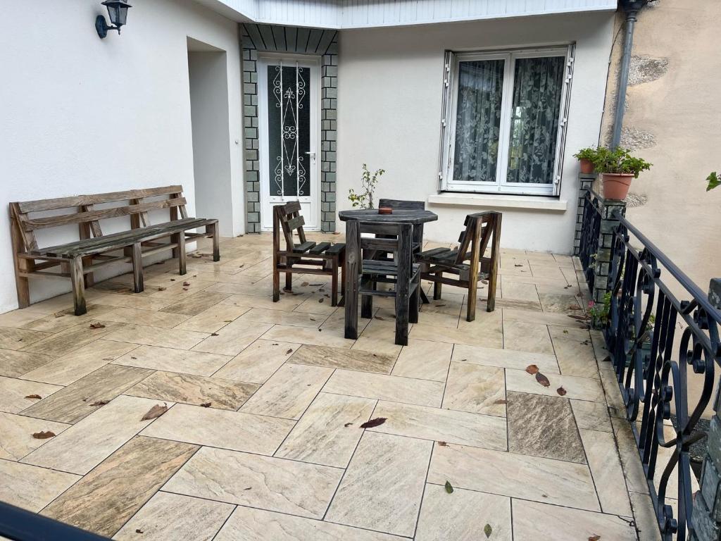 a patio with a table and chairs and a bench at Entre mûres et châtaignes in Les Châtelliers-Châteaumur