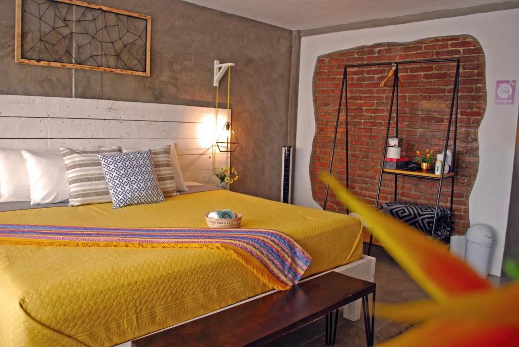 Un dormitorio con una cama amarilla y una pared de ladrillo en Casa Flora Handmade Hotel, en Atlixco