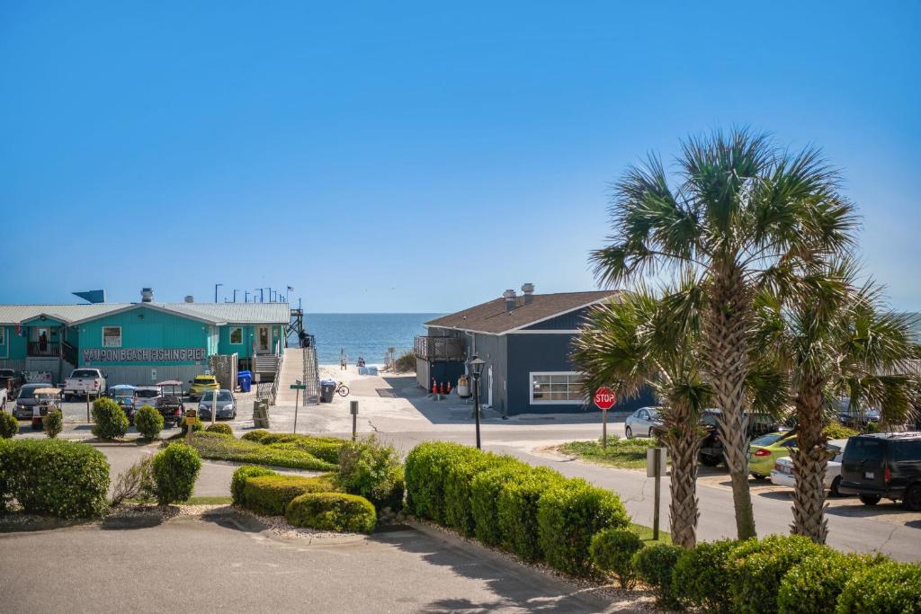 a street in front of a beach with houses and palm trees at The Dunes in Oak Island