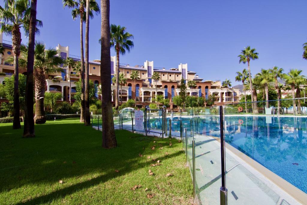 een resort met een groot zwembad met palmbomen bij 797 HOLIDAY RENTALS - BELLAGIO- Elegante piso para 6 a 1 min de la playa, con piscina interior y exterior, SPA con jacuzzi in Benalmádena