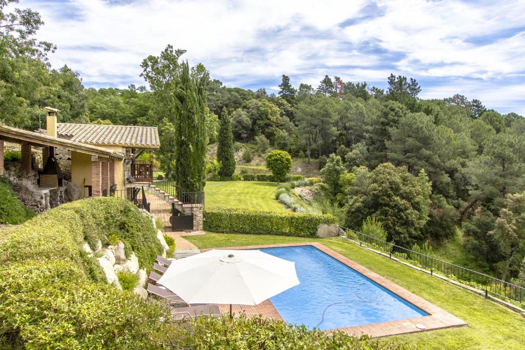 een landgoed met een zwembad en een parasol bij Catalunya Casas Stunning Costa Brava mountain retreat and 30kms away from the beach in Sant Feliu de Buixalleu