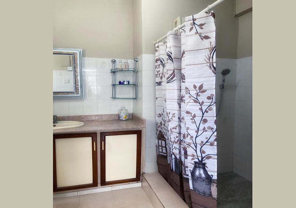 a bathroom with a shower curtain and a sink at R Garden Villa au calme de Baie du tombeau, Appartement familiale de 2 chambres et cuisine in Baie du Tombeau