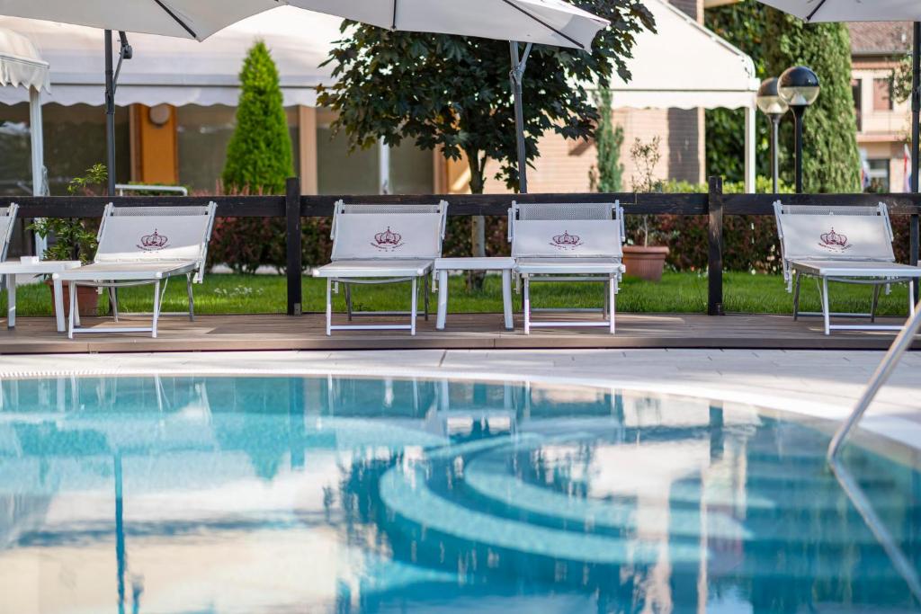 duas cadeiras e um guarda-sol junto a uma piscina em Hotel Imperial ***S em Garda
