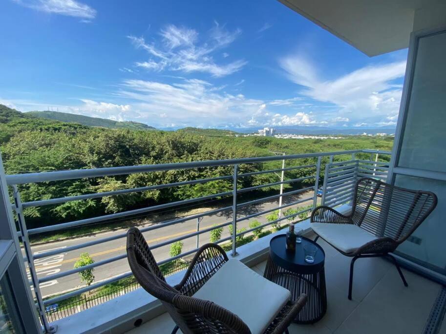 a balcony with chairs and a table and a grill at Ven a recargar energías. in Girardot