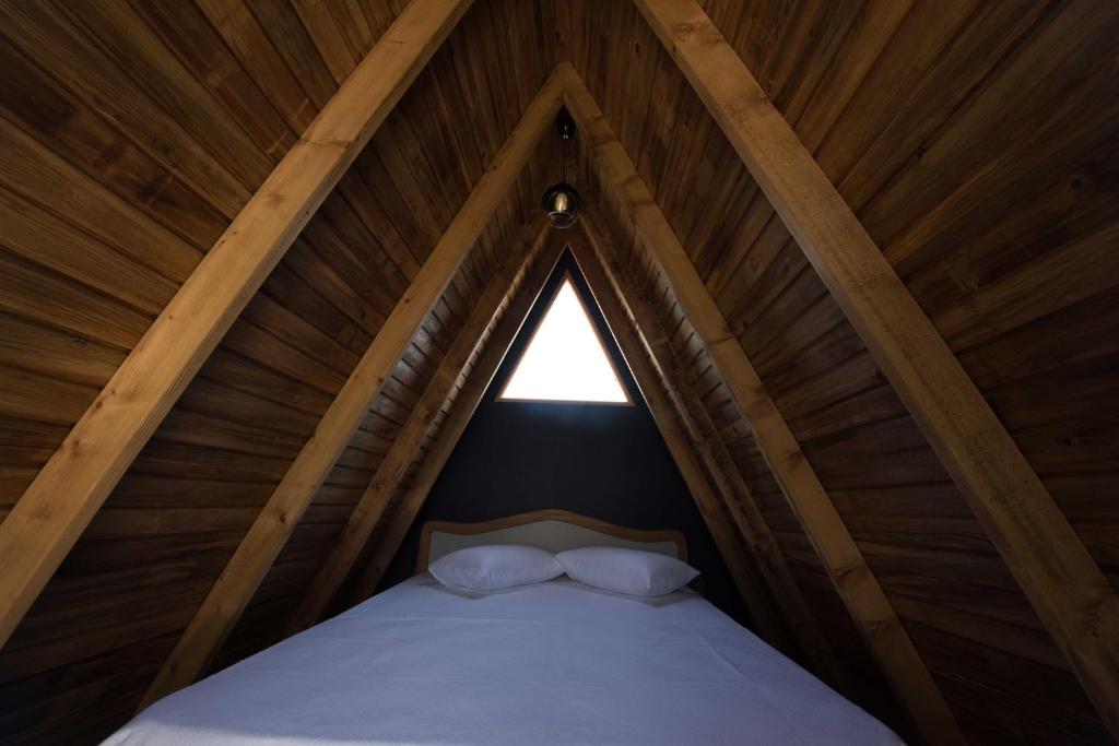 a bed in a wooden tent with a window at Byelka Bungalov Ayvalık in Ayvalık