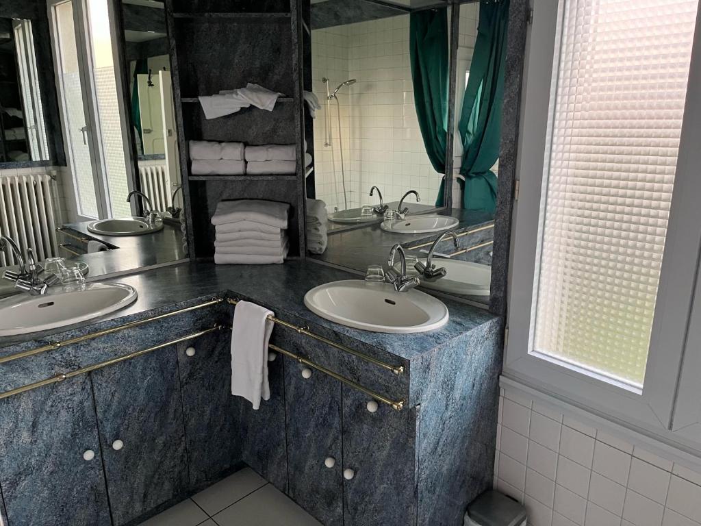 a bathroom with two sinks and a large mirror at Entre mûres et châtaignes in Les Châtelliers-Châteaumur