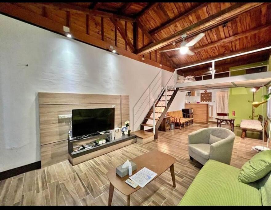 ein Wohnzimmer mit einem Sofa, einem TV und einer Treppe in der Unterkunft Humble Room in Hualien