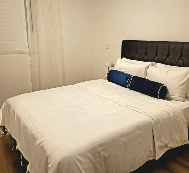 Una cama blanca grande con una almohada azul. en Nucleo 514, en San José