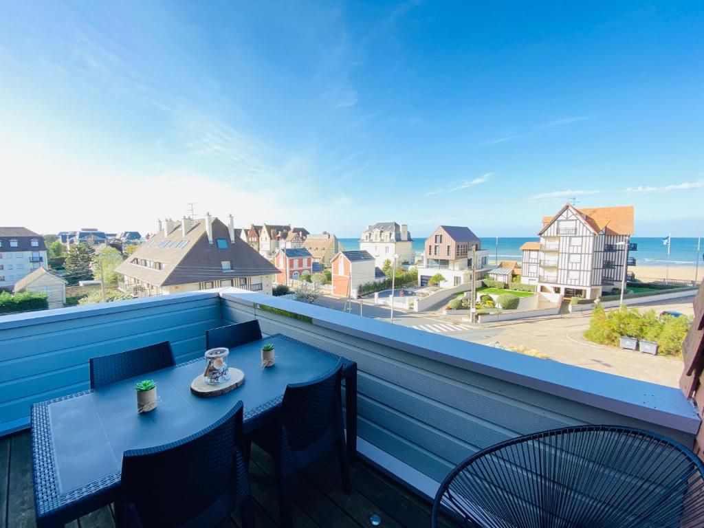 une table et des chaises sur un balcon avec vue sur l'océan dans l'établissement Le Balbec vue sur mer, à Cabourg