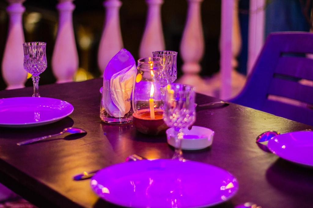 a table with purple plates and glasses on it at Baga Beach Myron in Baga