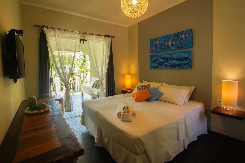 a bedroom with a large white bed and a window at Flor da Mata in Pipa