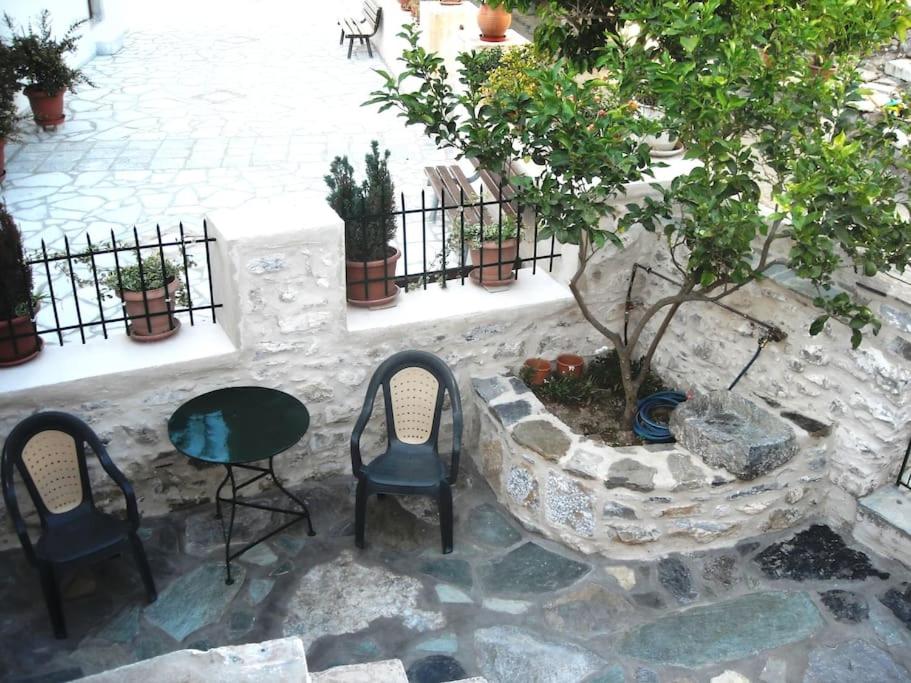 a patio with two chairs and a table and a tree at MARIA'S Rustic stonehouse in traditional village in Koúmani