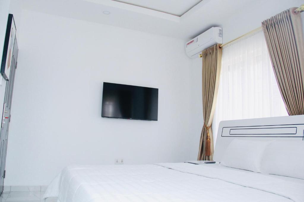 a white room with a bed and a tv on the wall at Jama Residence in Abuja
