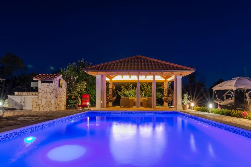 a swimming pool in front of a gazebo at night at House vacation with pool,near Šibenik in Planjane