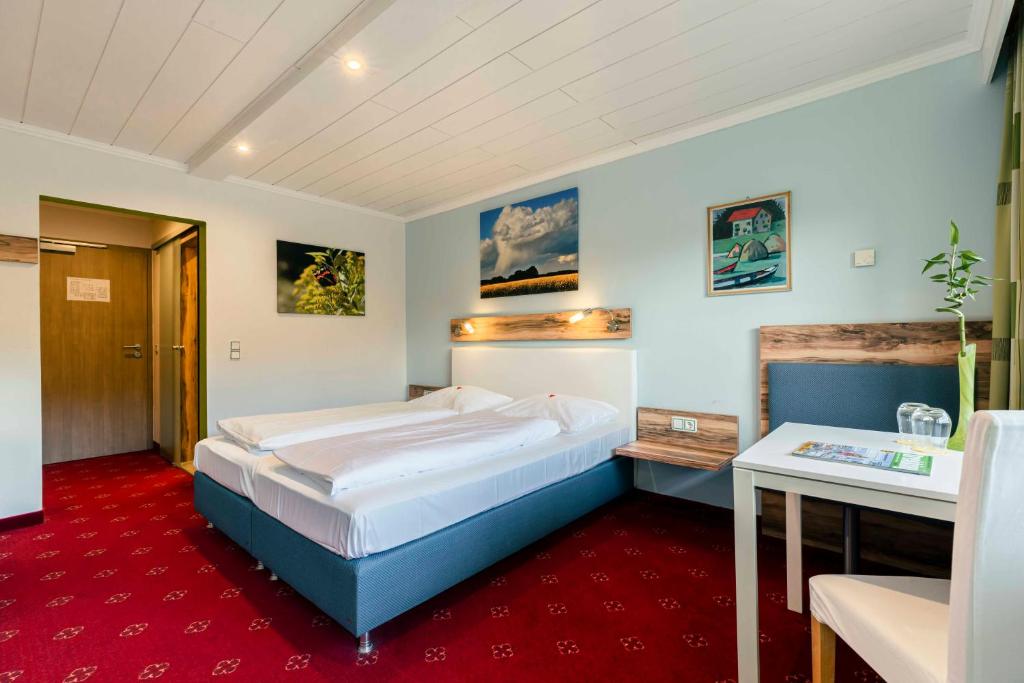 a bedroom with a large bed and a desk at Landhotel GrünWies -Bonsai-Wellness Garni in Lohberg