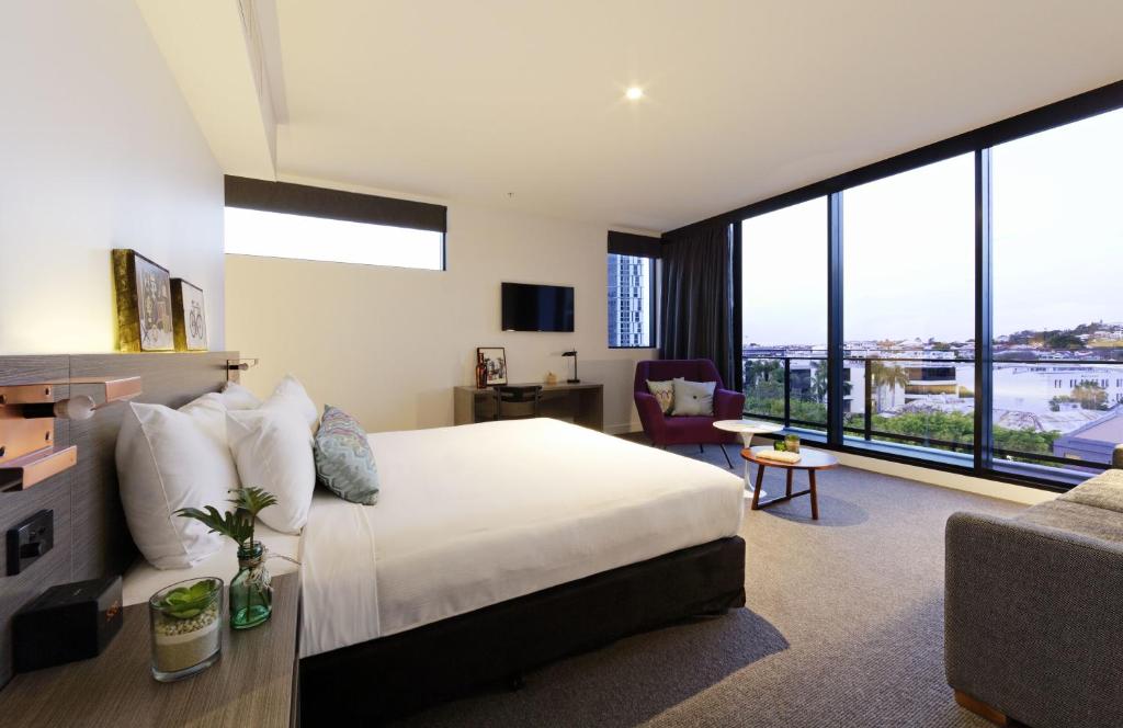 um quarto com uma cama grande e uma sala de estar em Alpha Mosaic Hotel Fortitude Valley Brisbane em Brisbane