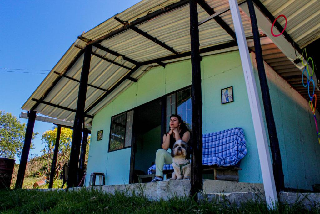 una mujer sentada en una ventana de una casa con un perro en Acogedora cabaña entre las montañas de La Calera- Colombia, en La Calera