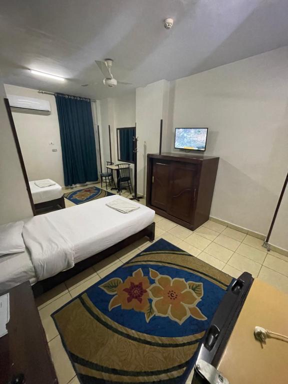 QināにあるGrand Hotel Qenaのベッドとテレビが備わるホテルルームです。