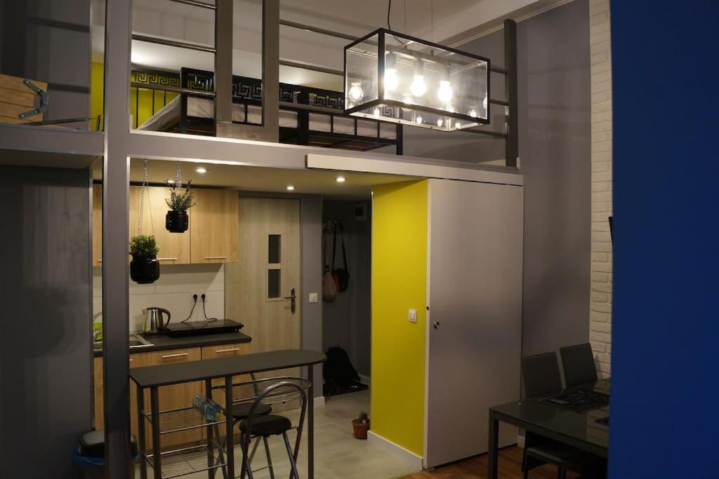 a kitchen and a dining room with a yellow wall at Apartament Zielony Legionów 90 in Łódź