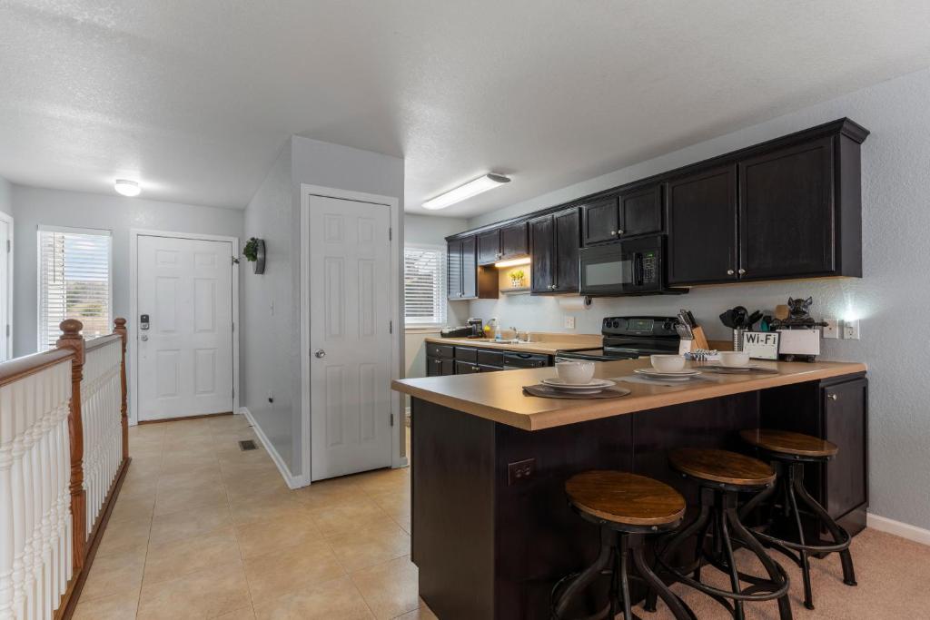 a kitchen with black cabinets and bar stools at Rustic Theme, King Bed, Free Parking with Extra Street KMS1305 in Manhattan