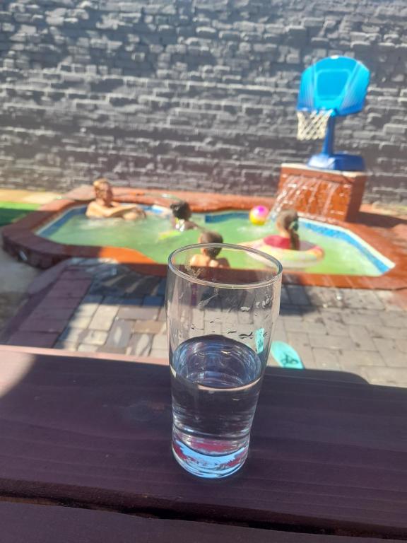 a glass of water sitting on a table next to a swimming pool at Cozy guesthouse-springs in Springs