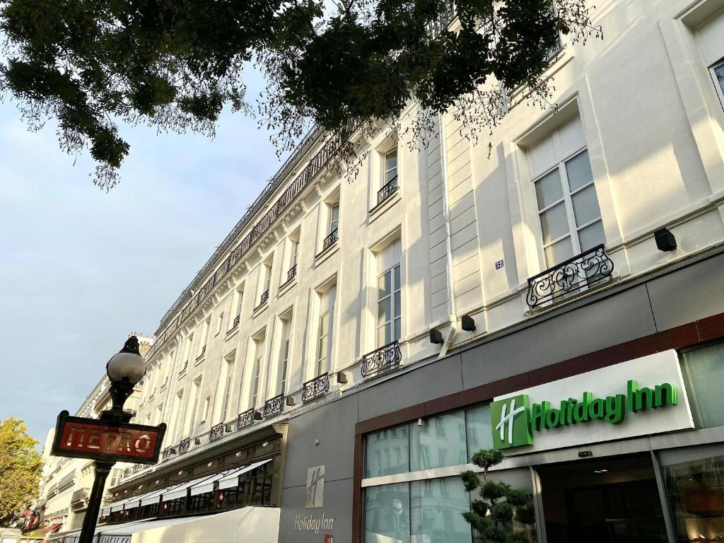 un gran edificio blanco con un cartel delante en Holiday Inn Paris Opéra - Grands Boulevards, an IHG Hotel, en París