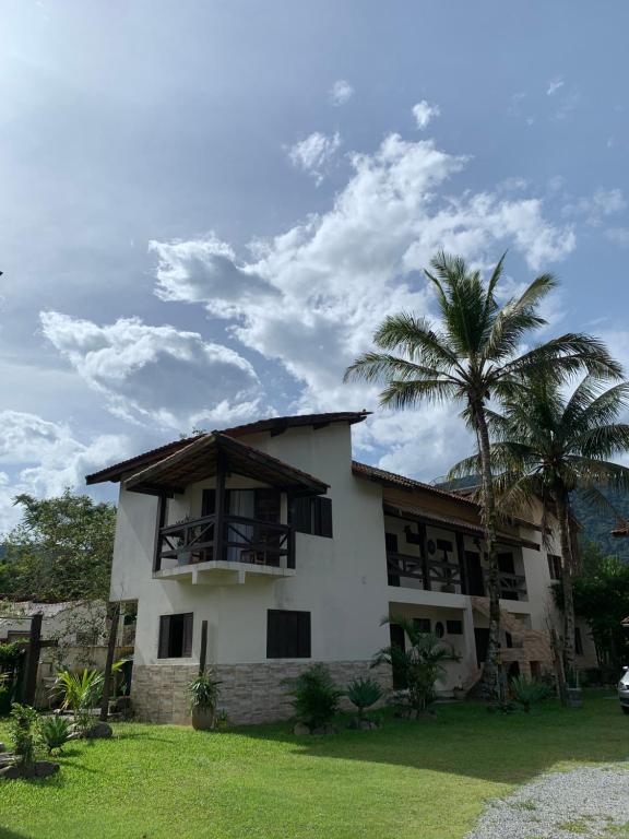 una casa con una palmera delante en Suítes Maresias, en Maresias