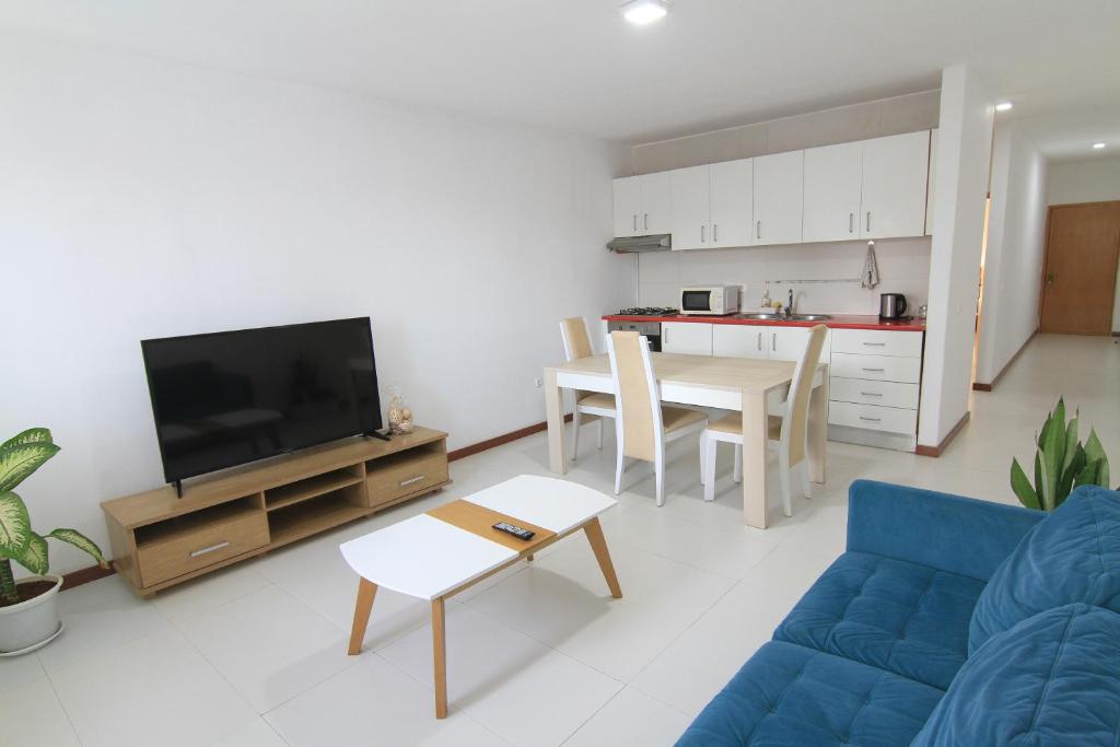 ein Wohnzimmer mit einem blauen Sofa und einer Küche in der Unterkunft Quick Stay in Praia #2 in Praia