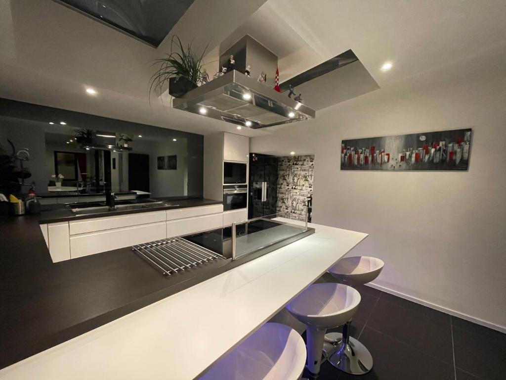 a kitchen with a white counter and stools at Modern 1BR house near Heysel, Expo, Palais 12, Atomium, UZVUB et stade Roi Baudouin in Wemmel