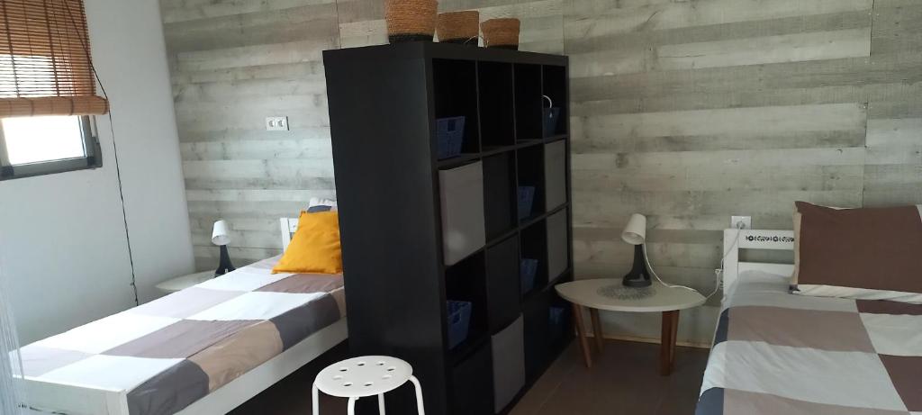 a bedroom with two beds and a black book shelf at Apartamento Cerezo Beach in Xilxes