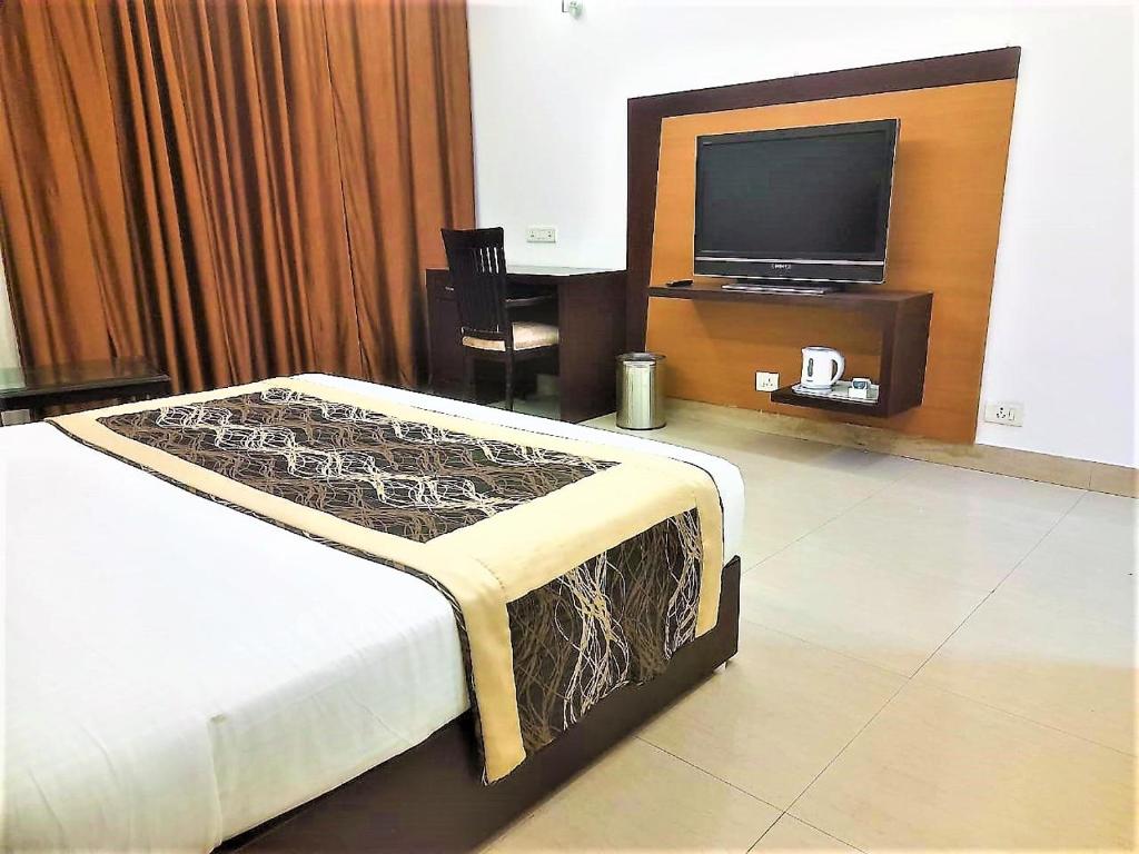 - une chambre avec un lit et une télévision à écran plat dans l'établissement Tavisha Villa Flim City Road Dadri Road, à Noida