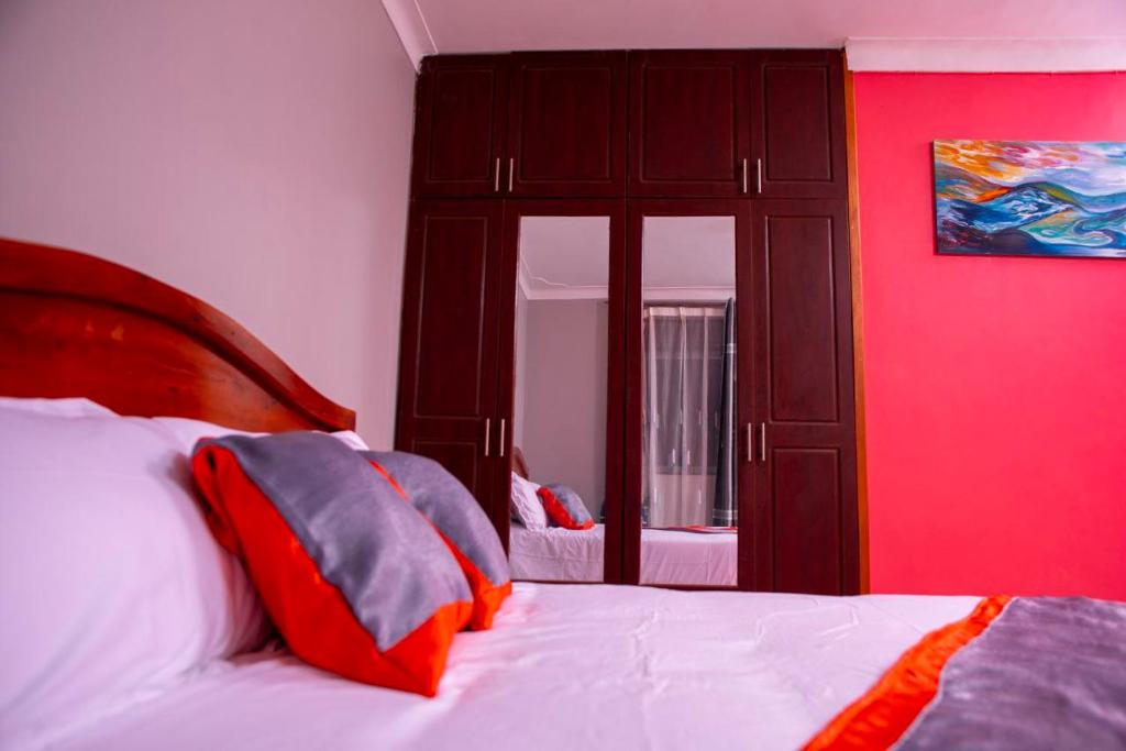 a bedroom with a bed with a red wall at Karay Apartments in Wakiso