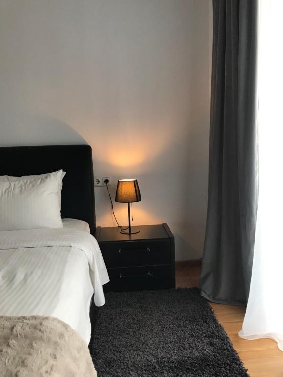 a bedroom with a bed and a lamp on a night stand at Comfortable Apartment in Cartier Evocasa Orizont Ploiesti (North) in Ploieşti