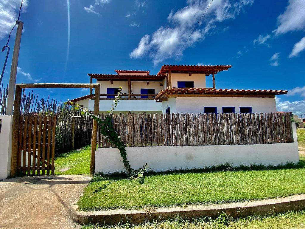 una casa detrás de una valla de madera con una puerta en Pousada Le Petit Suítes ER Hospedagens, en Porto de Pedras