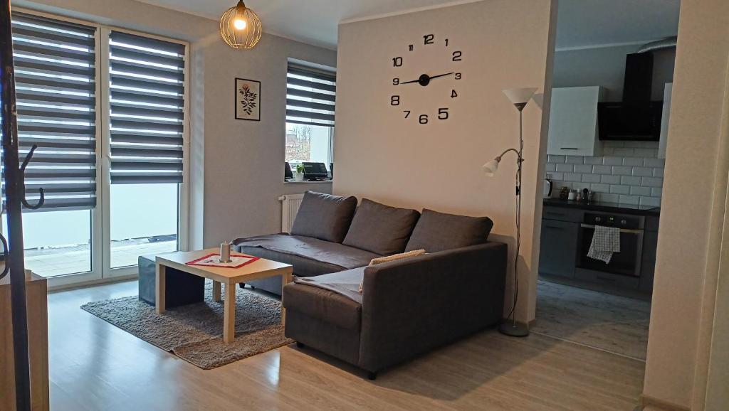 a living room with a couch and a clock on the wall at Apartament Blondynka Miasto Soli Bochnia in Bochnia
