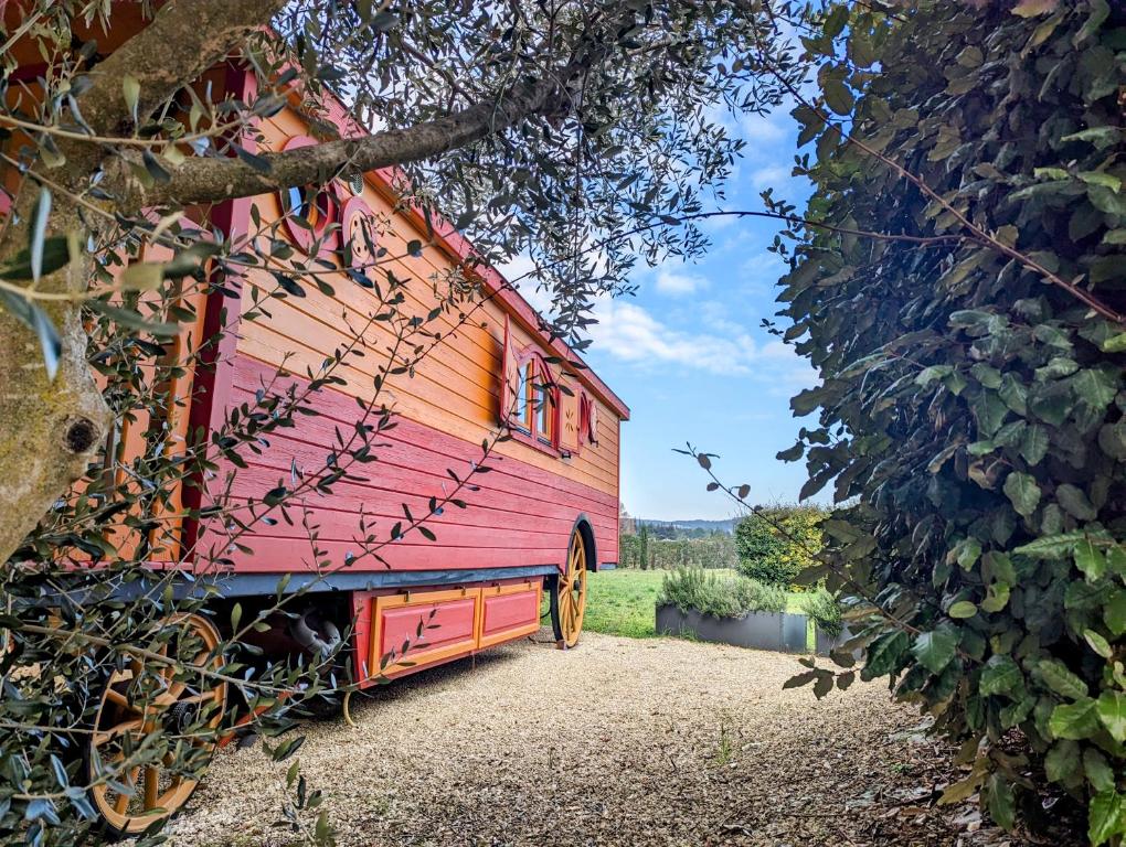 a red barn sitting on the side of a house at Roulotte chez Manon en Luberon in Lagnes