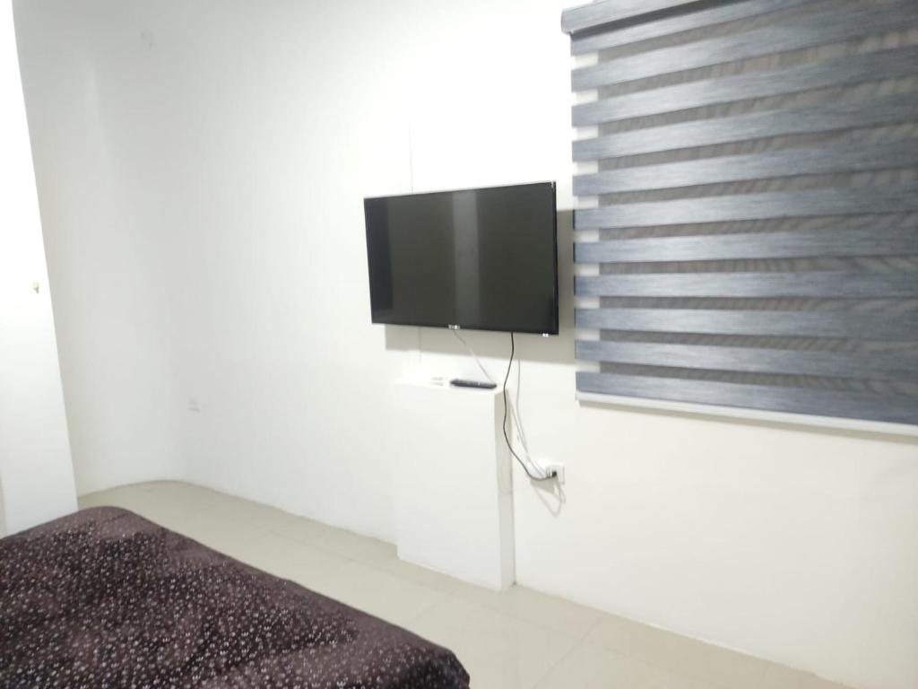 1 dormitorio con TV de pantalla plana en la pared en SUITE MODERNA E INDEPENDIENTE CON PARQUEO PRIVADO, en Portoviejo