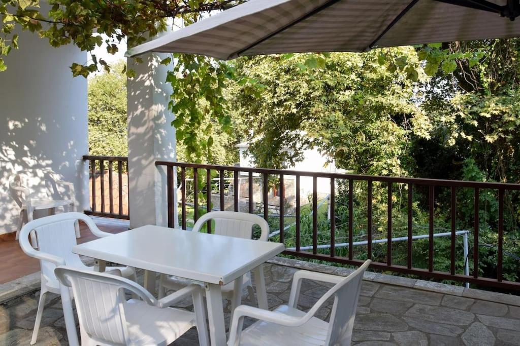 a white table and chairs on a balcony with an umbrella at Apartment in summer house with large balcony in Chorefto