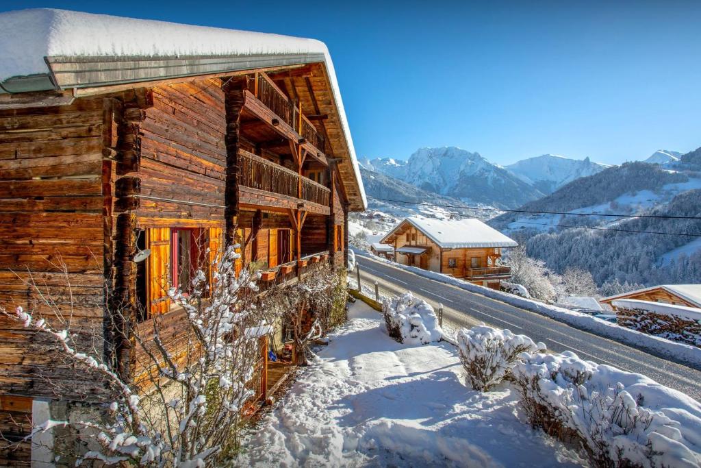 una baita di tronchi nella neve con montagne sullo sfondo di Chalet Cashmere Spirit - OVO Network a Manigod