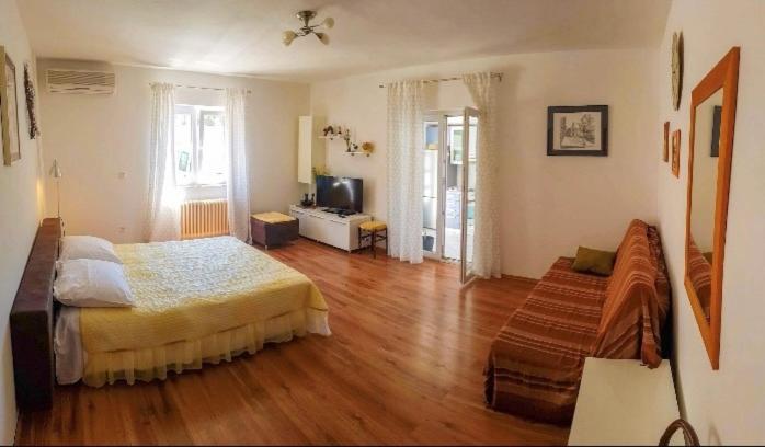 een slaapkamer met een bed en een houten vloer bij Apartmani Tina in Jelsa