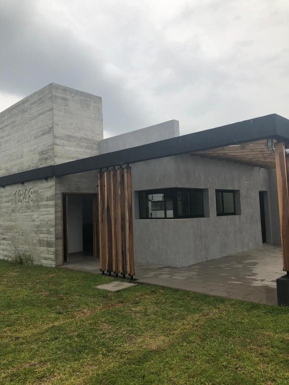 un edificio de hormigón con puertas de madera en un patio en CASA ALQUILER PINAMAR en Pinamar