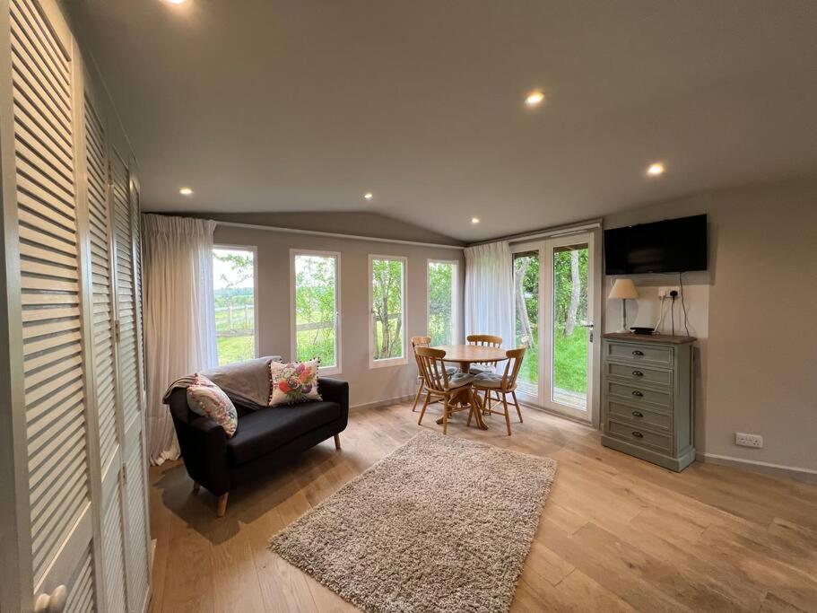 a living room with a couch and a table at Log Studio near Le Manoir aux Quat’Saisons, Oxford in Great Milton