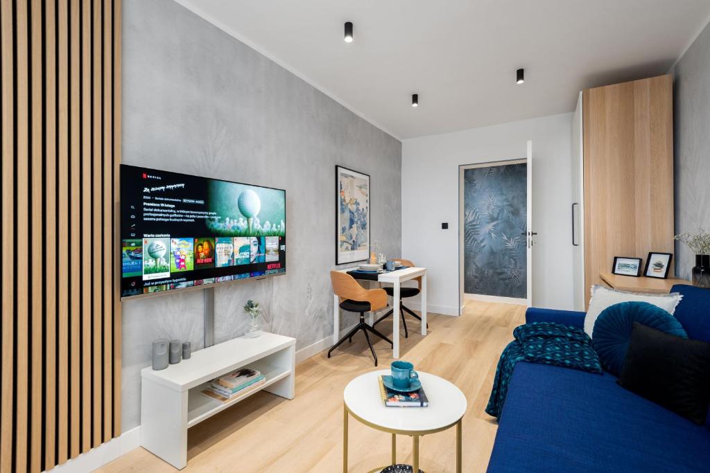 ein Wohnzimmer mit einem blauen Sofa und einem TV in der Unterkunft Apartament Gold - darmowy Parking, ścisłe centrum - by Kairos Apartments in Gliwice