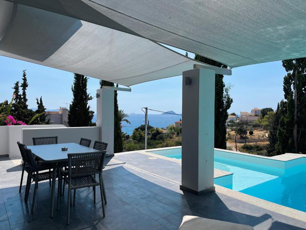 波多河麗的住宿－Porto-Cheli Sunset View House，一个带桌椅的庭院和一个游泳池