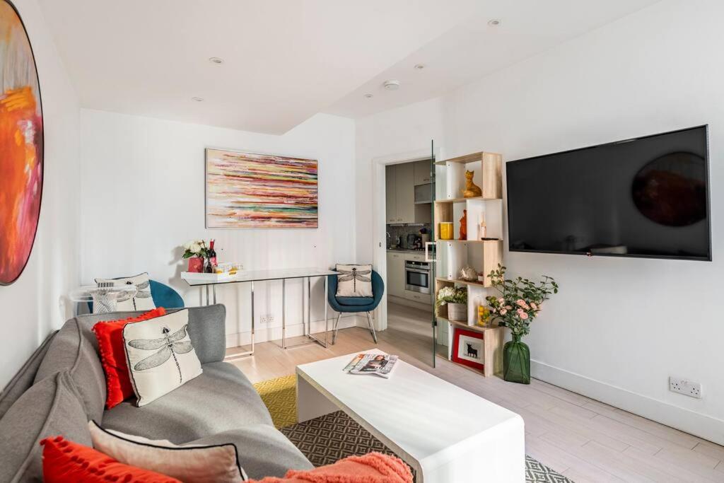 a living room with a couch and a tv at Chelsea Posh apartment in London