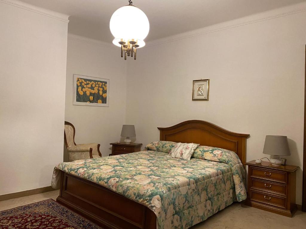 a bedroom with a bed and two tables and a chandelier at CASA DELLA PIAZZA in Bagnone