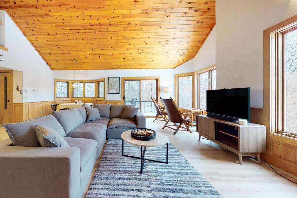 uma sala de estar com um sofá e uma televisão em White Mountain Chalet em Bartlett