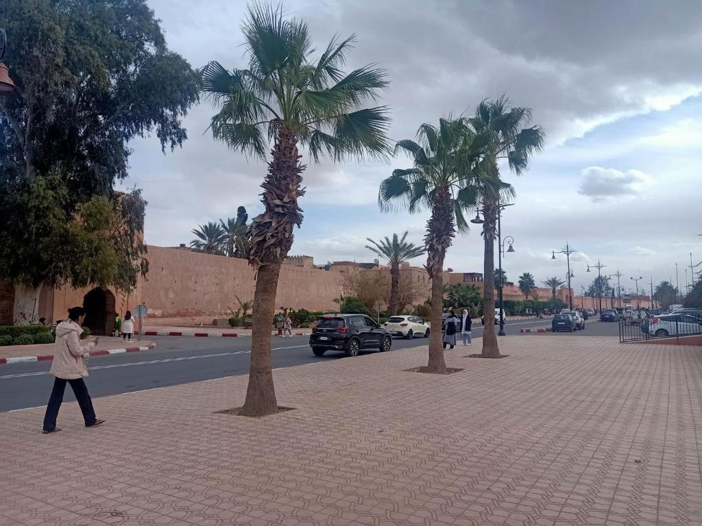 een man die over een straat loopt met palmbomen bij Dar 36 LAKSIBA in Marrakesh