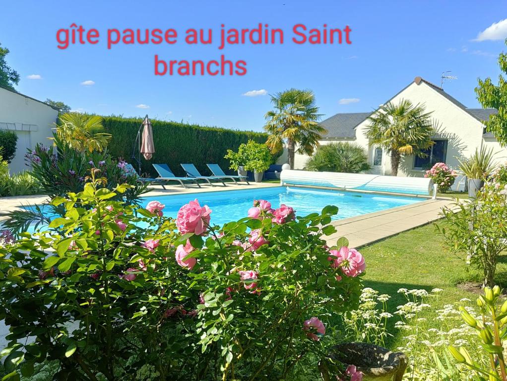 a house with a swimming pool with pink flowers at Gîte pause au jardin in Saint-Branchs
