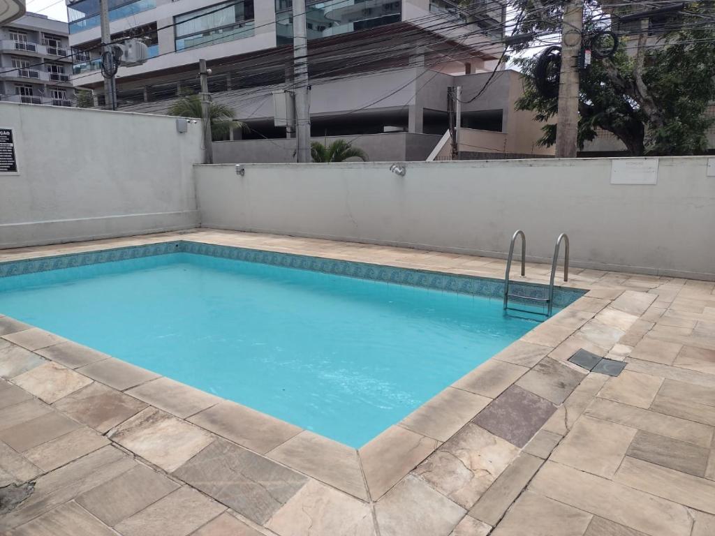 a swimming pool with blue water in a building at Apartamento Praia do Forte Familiar com piscina in CFB
